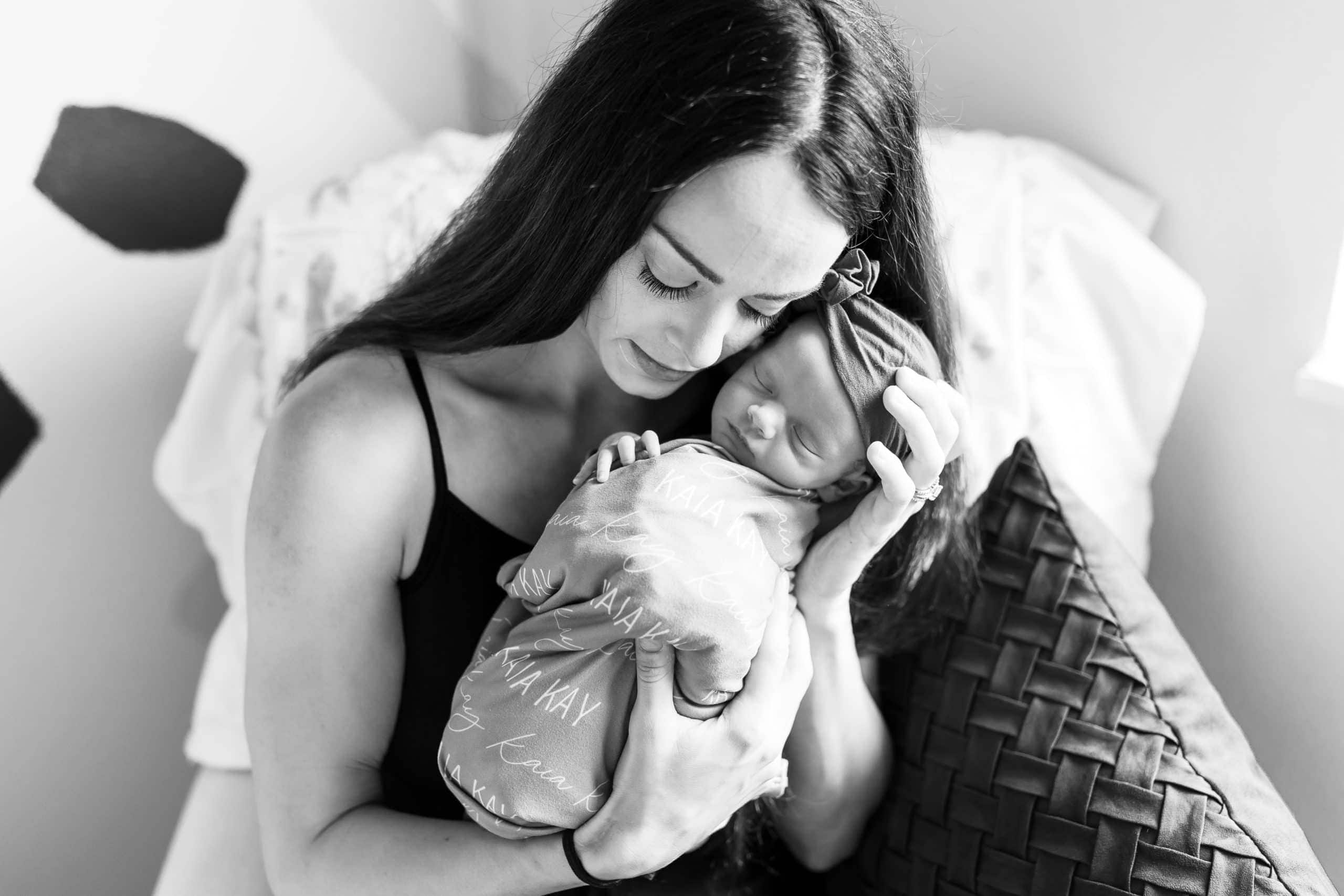 Mother cuddles her newborn baby close to her face in black and white image by haili wright photography