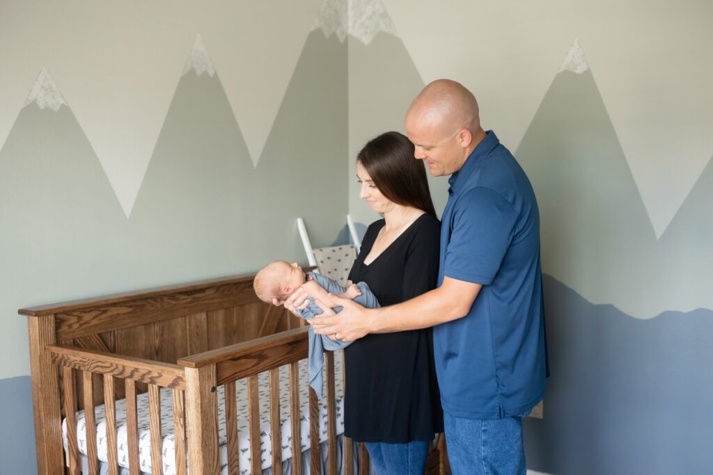 Parents holding new baby in mountain-themed nursery