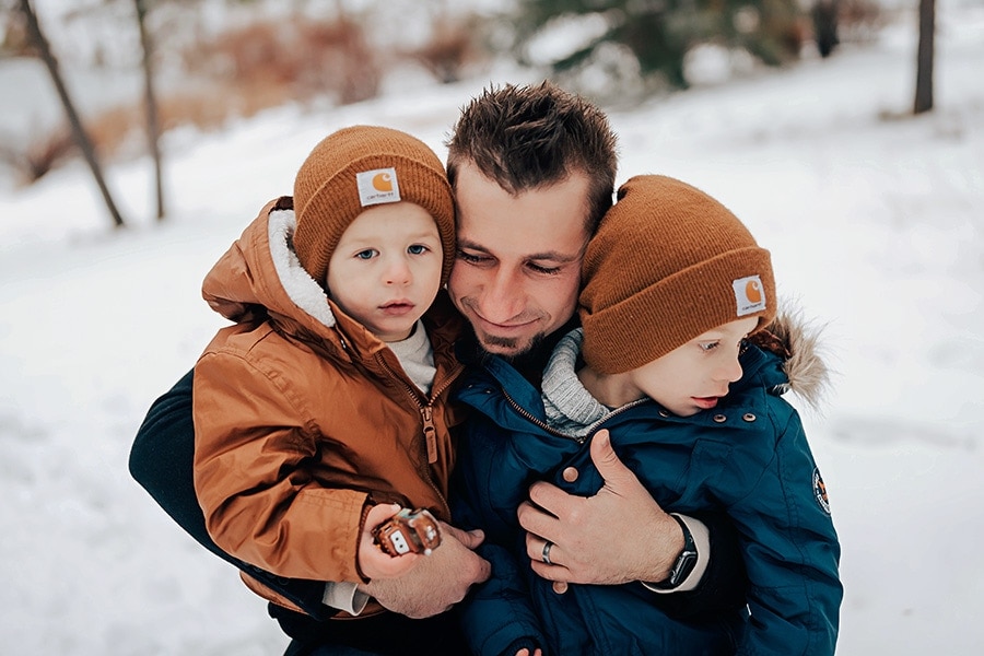 Dad hugging young sons in the snow