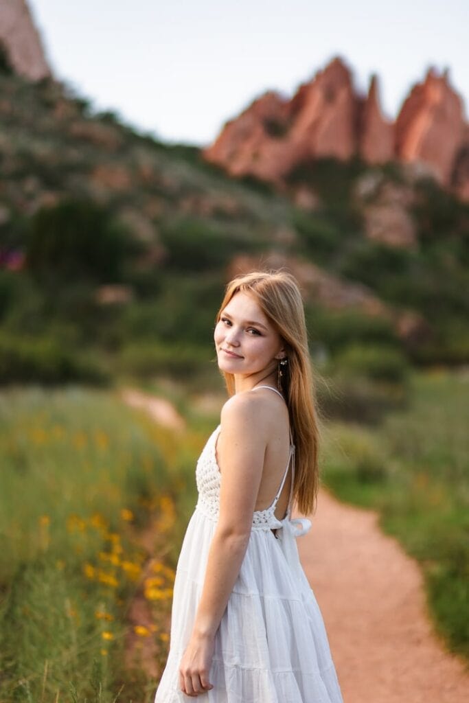 Teen girl in white sundress posing for high school senior photos in Garden of the Gods