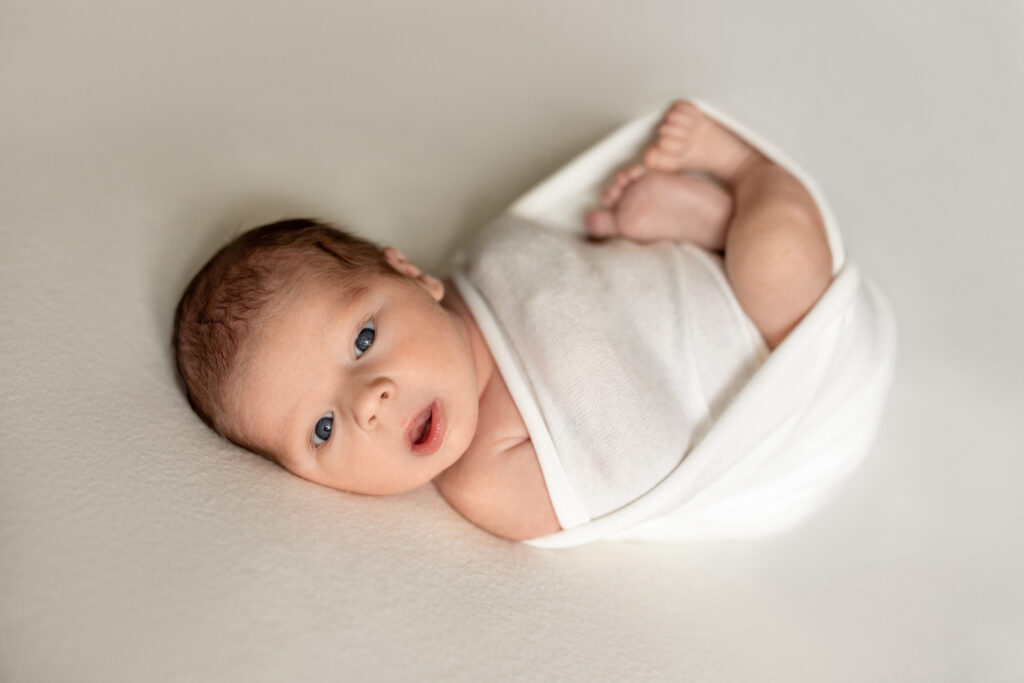Baby boy securely wrapped in white swaddle