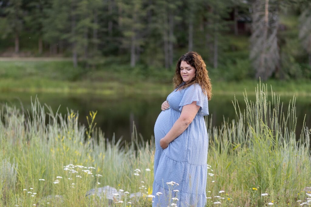 Woman in blue maternity dress by mountain lake in Colorado Springs