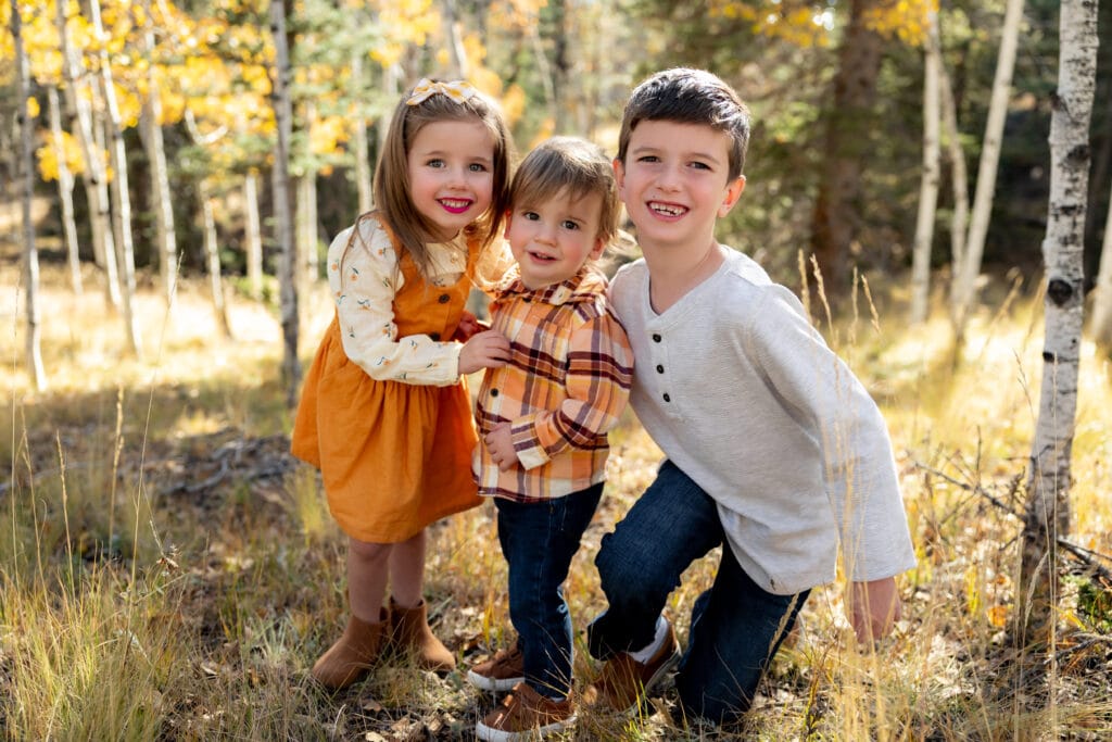 Trio of siblings hugging during fall family portraits in Colorado