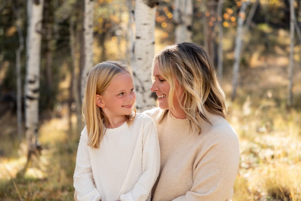 Mom and daughter smiling at each other during outdoor fall family mini sessions in Woodland Park