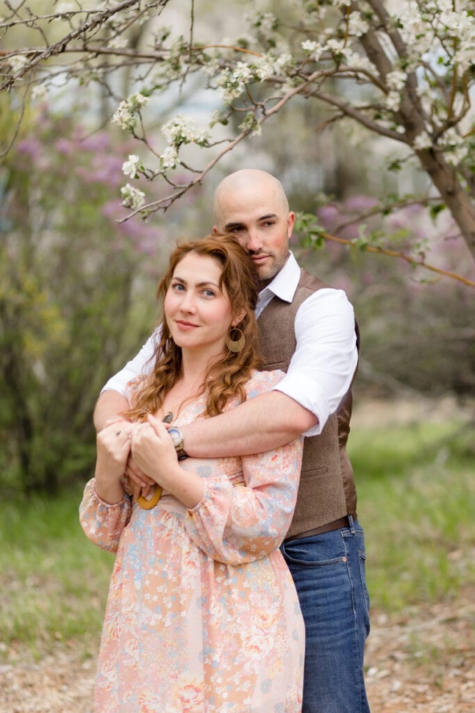 Couple embraces under a blossoming tree in a park in Colorado Springs