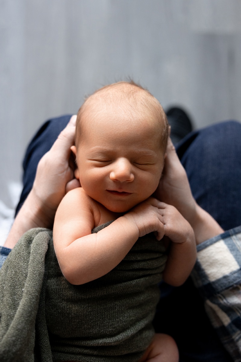 Newborn Photography, newborn baby laying on parents legs, sleeping in their arms