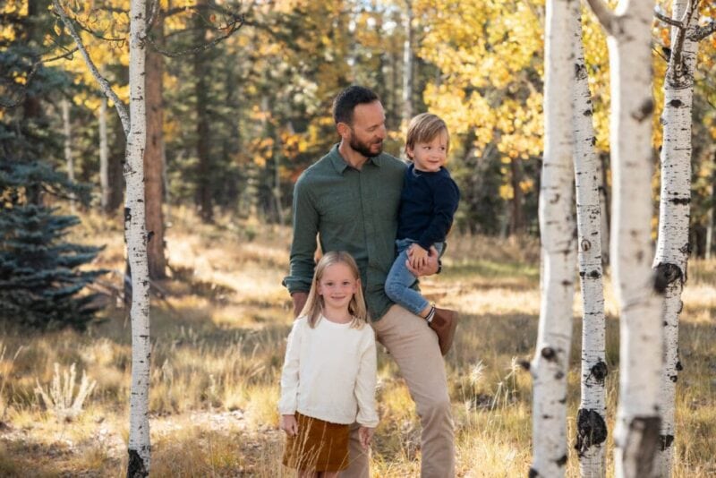 Dad standing in a grove of aspen trees with his two young children