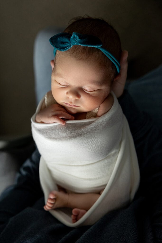 Sweet baby girl in swaddle and bow during newborn photoshoot in Peyton Colorado