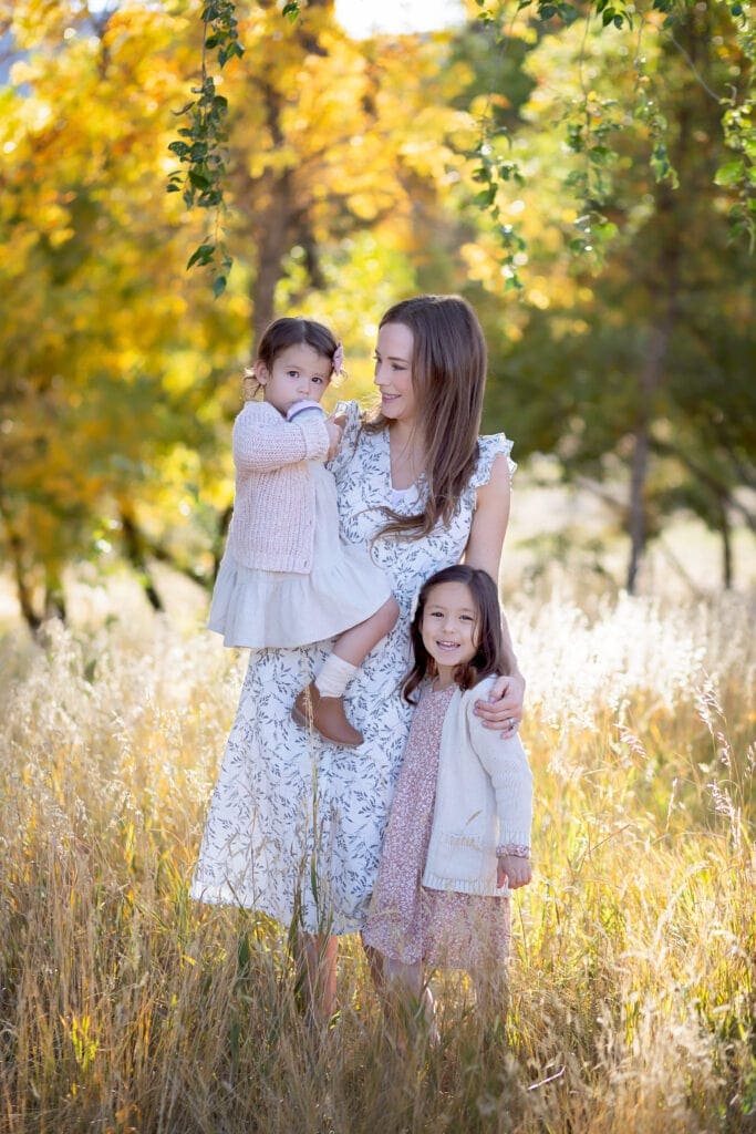 Mom and daughters against backdrop of fall foliage