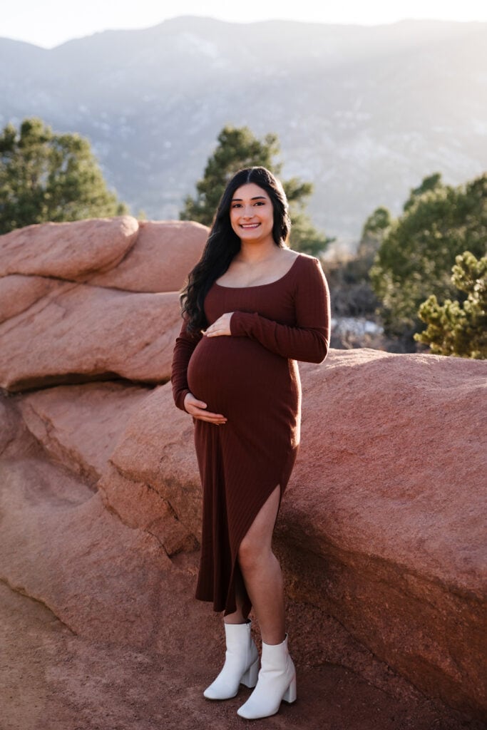 Pregnant woman in casual slit dress standing against rock formation in Colorado Springs